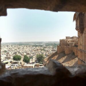 Distant ancient stone buildings of aged town with wall of medieval fort in India